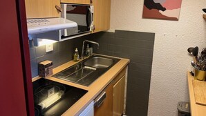 A compact kitchen with a microwave, sink, and wooden cabinets.