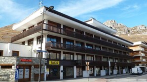 A multi-story hotel with balconies, a taxi stand, and a sign for 'Residence Alpes 1'.