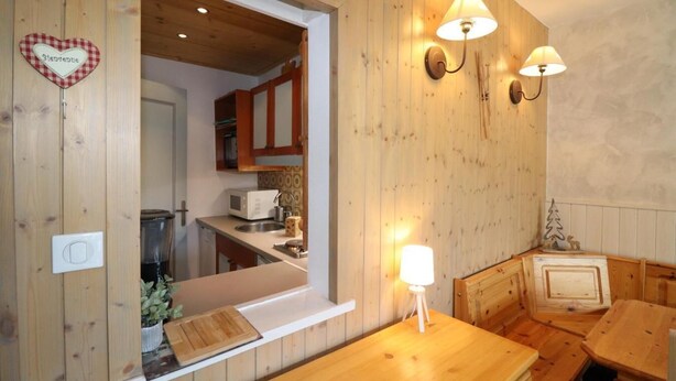A wooden interior with a kitchen area, wooden walls, and a dining table.
