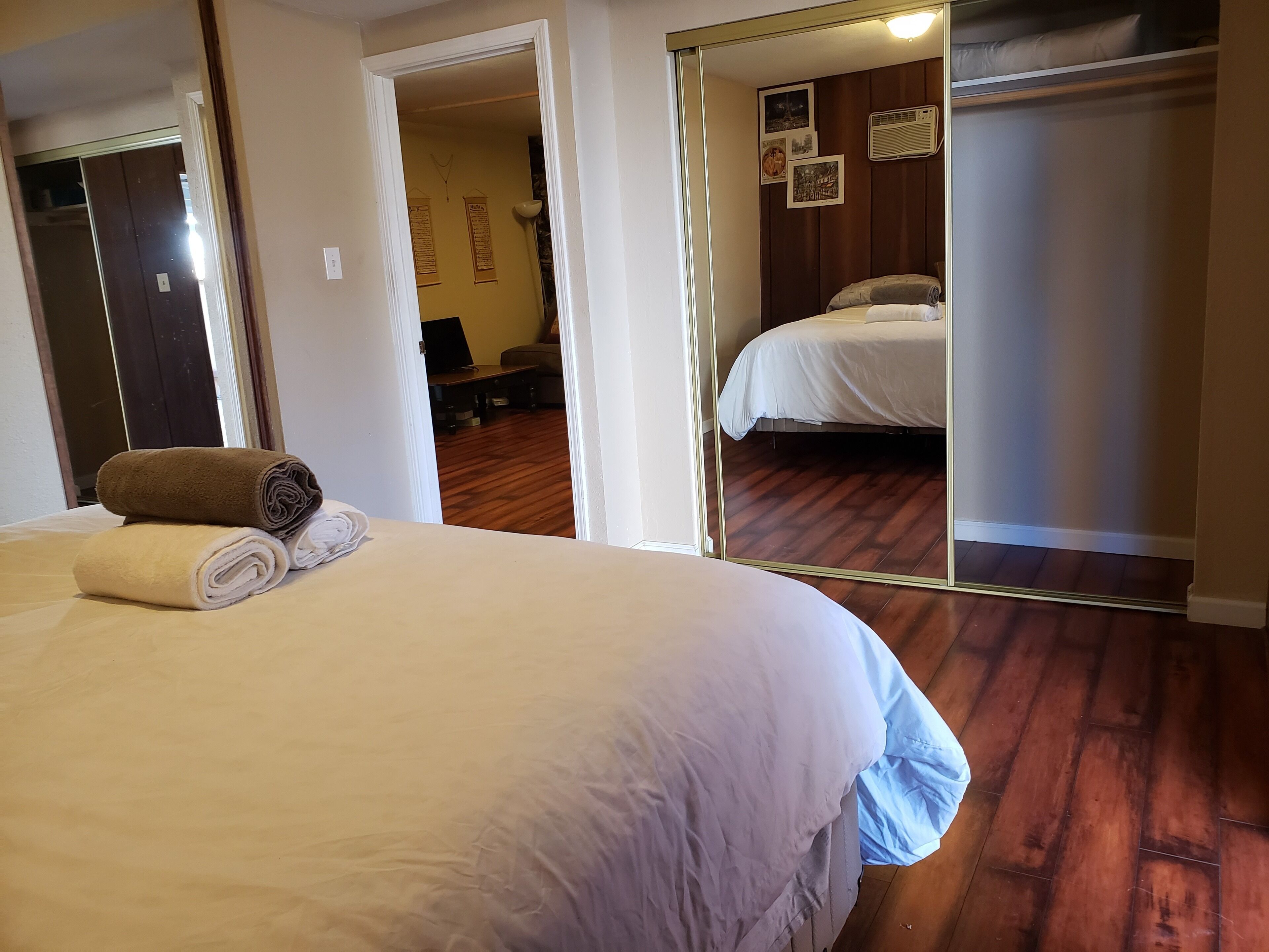 Een slaapkamer met een groot bed, een spiegel en een houten vloer.