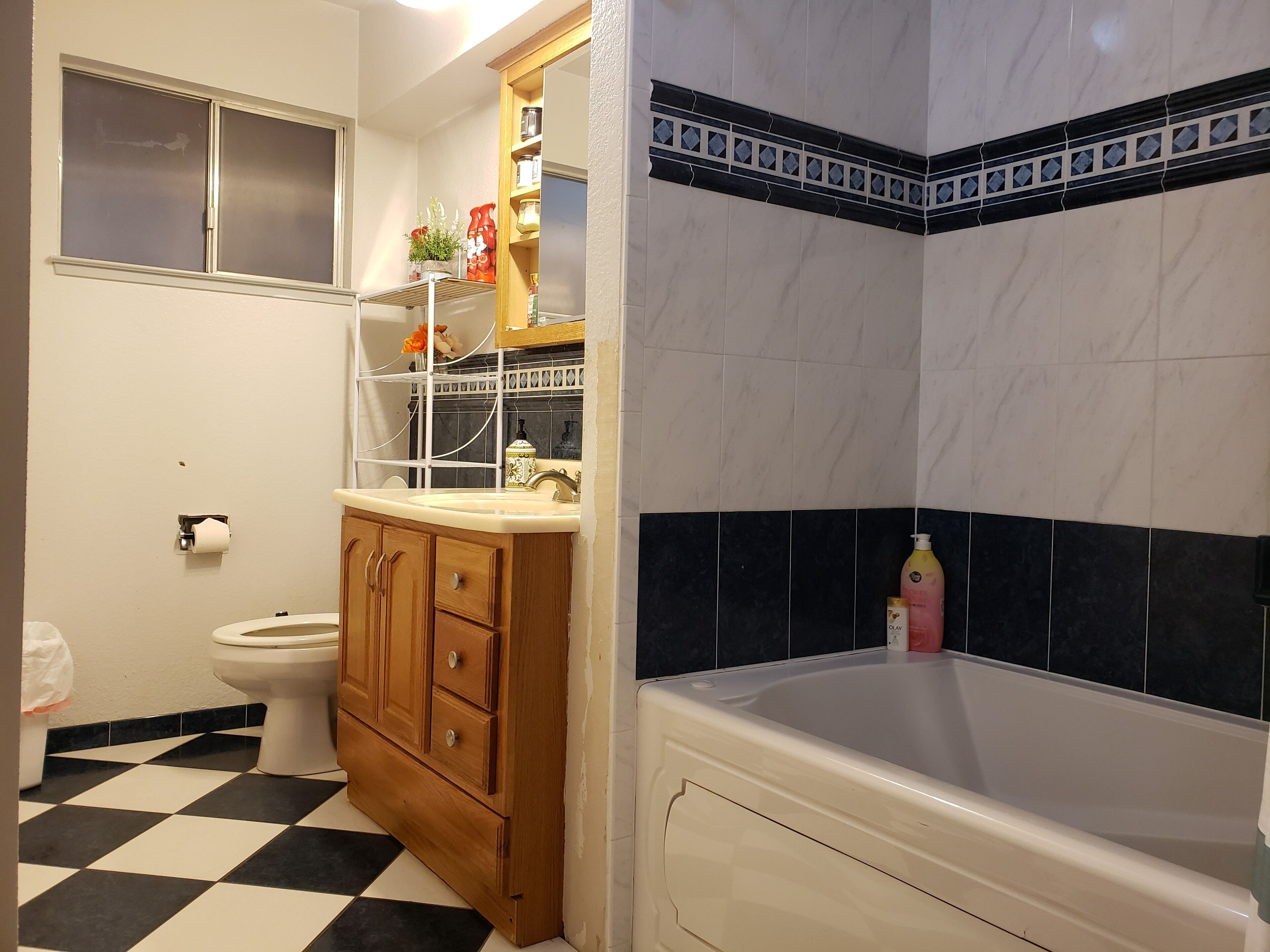 A bathroom with a toilet, a wooden cabinet, a sink, and a bathtub.