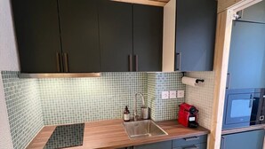 A modern kitchen with dark cabinets, a wooden countertop, and a tiled backsplash. - 100m from ski slopes, 2nd floor, balcony, tv, 25m², Tignes (Tignes)