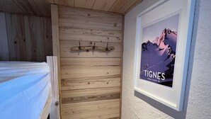 A room with a wooden slatted wall, a framed picture of a mountain, and a bunk bed. - 100m from ski slopes, 2nd floor, balcony, tv, 25m², Tignes (Tignes)