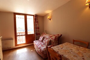 Cozy room with a single bed, wooden chair, and sliding glass door leading to a balcony.