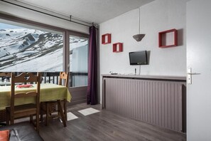 Enjoy a serene view of the snowy landscape from the comfort of this cozy room, featuring a dining table, flat-screen TV, and stylish decor.