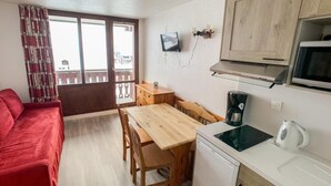 A compact kitchen with a wooden table, a coffee maker, a kettle, and a microwave. - 100m from resort center, 4th floor, balcony, ski locker, 18m², Tignes (Tignes)