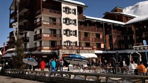 A multi-story hotel with balconies, outdoor seating, and a ski slope in the background. - 100m from resort center, 4th floor, balcony, ski locker, 18m², Tignes (Tignes)