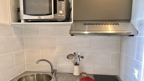 A kitchen with a stainless steel sink, a microwave, a stove, and a white tiled backsplash. - 300m from ski slopes, Ground floor, balcony, tv, 23m², Tignes (Tignes)