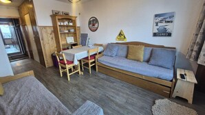 A cozy room with a wooden sofa, a dining table with chairs, a small wooden cabinet, and a framed picture on the wall. - 300m from ski slopes, Ground floor, balcony, tv, 23m², Tignes (Tignes)
