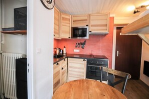 Uma cozinha compacta com armários de madeira, micro-ondas, forno e pia.