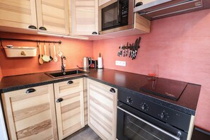 Kitchen features a sink under a window, stainless steel appliances, and wooden cabinetry.