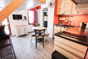 Cozy kitchen with dining area, featuring a round table and two chairs, and a television mounted on the wall.