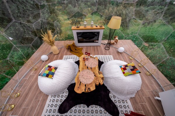 A cozy outdoor seating area with a wooden table, white poufs, and a central wooden log. - Hayal Tadında (Odemis)