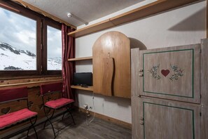 Cozy retreat with a wooden bench, foldable chair, and TV on a wooden shelf, offering a serene view of the surrounding landscape.