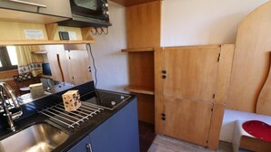 A compact kitchen with a sink, stove, and microwave. There is a wooden cabinet and a red chair. - 10m from resort center, 11th floor, television, ski locker, 12m², Tignes (Tignes)