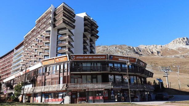 A multi-story building with balconies, a ski school sign, and a bank sign. - 10m from resort center, 11th floor, television, ski locker, 12m², Tignes (Tignes)