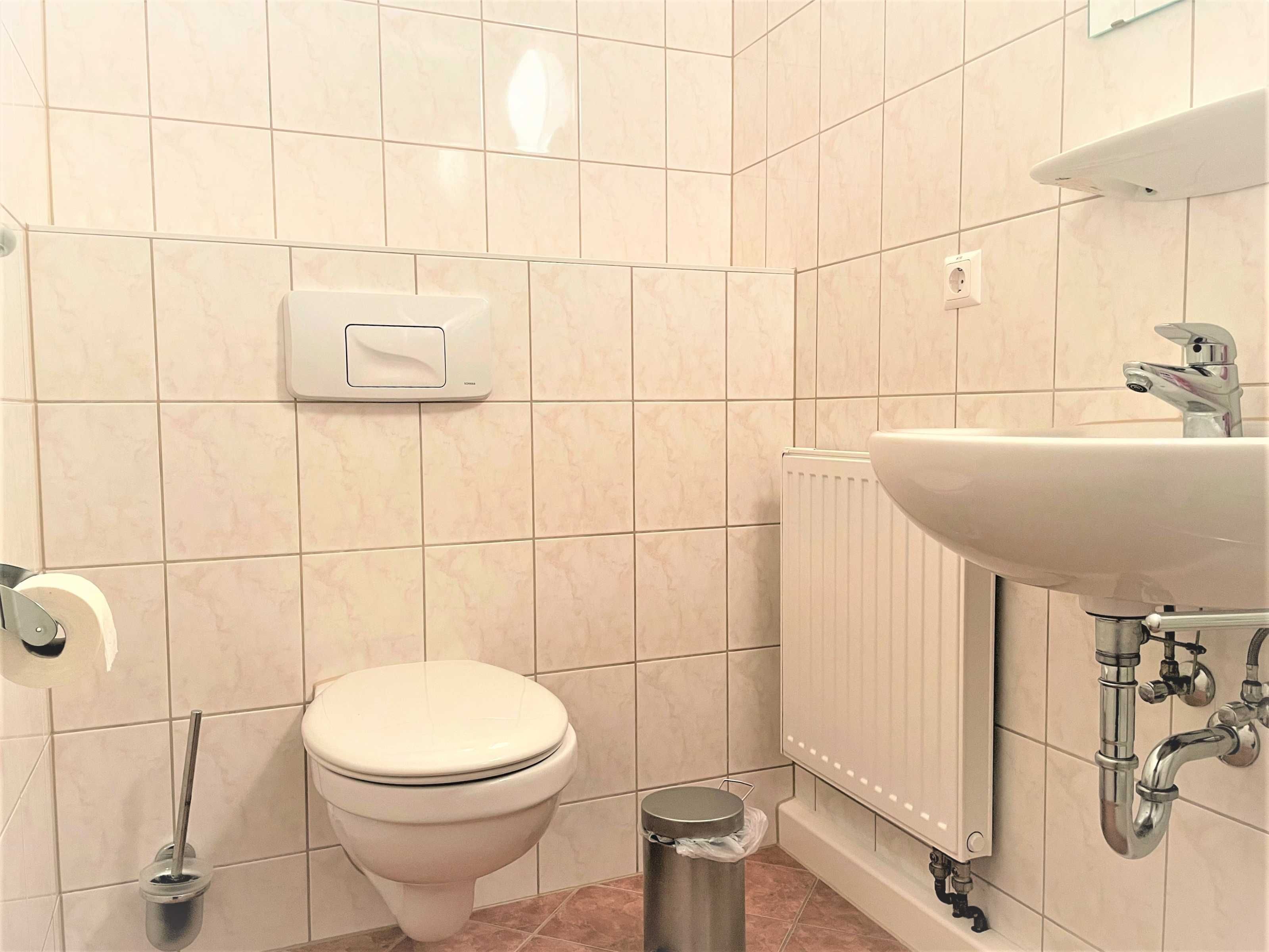 Une salle de bain équipée de toilettes, d’un sèche-mains, d’un radiateur et d’un lavabo avec un miroir.