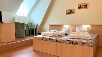Ein Schlafzimmer mit einem Schlafplatz im Loft-Stil, einem Schreibtisch und einem Stuhl. An den Wänden hängen zwei Gemälde.