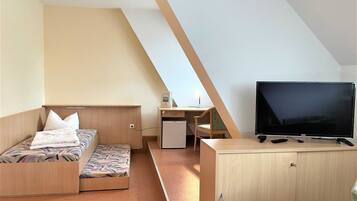 Ein gemütlicher Raum mit Bett, Schreibtisch, Fernseher und Schrank.