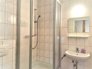 A bathroom with a glass-enclosed shower, a sink, and a mirror above it. - Ferienzimmer Nr. 34 - Schullandheim Reichwalde (Boxberg/Oberlausitz)