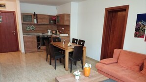 Een moderne woonkamer met een houten eettafel, zwarte stoelen, een grijze bank en een salontafel met decoratieve objecten.