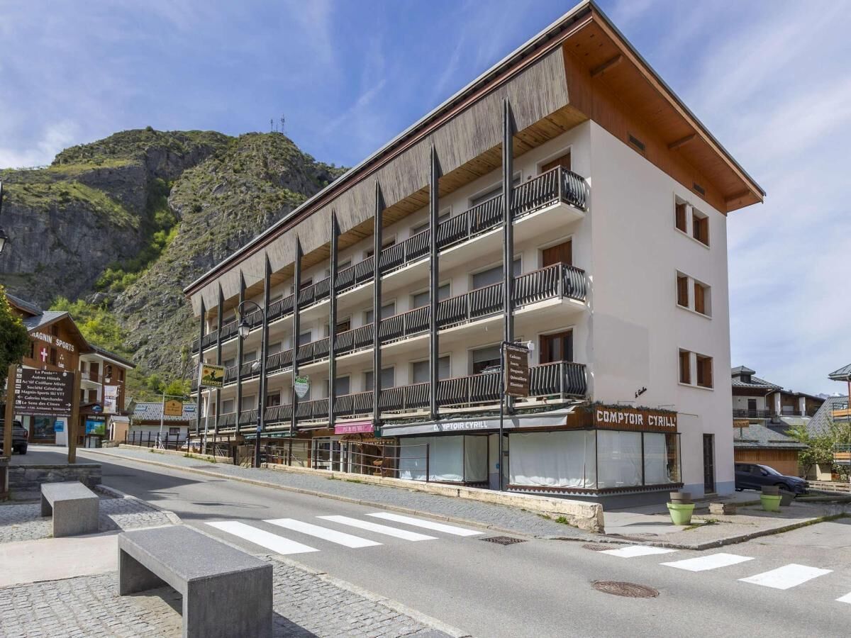 Ein mehrstöckiges Hotel mit Balkonen, einem Schild mit der Aufschrift 'Comptoir Cyrill' und einer bergigen Kulisse.