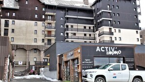 A multi-story building with a modern design, featuring balconies and a storefront labeled "ACTIV Immo". - 10m from ski slopes, 2nd floor, view ski slopes, balcony, tv, ski locker, 30m², Risoul (Risoul)