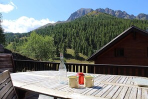 A wooden deck with a table, a bottle, and two mugs. A mountain range is visible in the background. - 100m from ski slopes, terrace, tv, 72m², Vars (Vars)