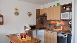 A compact kitchen with wooden cabinets, a microwave, a coffee maker, and a sink. - 50m from ski slopes, 3rd floor, view village/ski slopes, balcony, parking, tv, ski locker, 42m² (Montgenèvre)