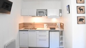 A compact kitchen with white cabinetry, a microwave, a coffee maker, and a dishwasher.