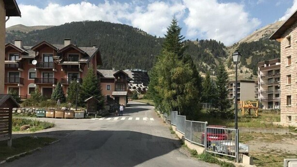 A mountain resort with multi-story buildings, a paved road, and a crosswalk.