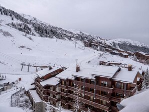 En fleretagers hytte med en skibakke i baggrunden.