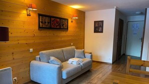 Ein gemütliches Zimmer mit einem grauen Sofa, Holzwänden und einem Holzessttisch.