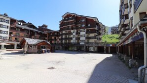 Une cour d’hôtel dallée de pierres, des immeubles à plusieurs étages dotés de balcons et une petite construction en bois.