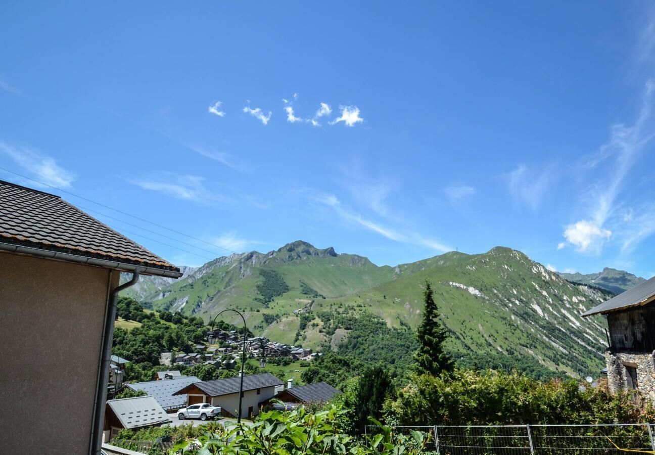 A mountain village with traditional houses, a clear sky, and a view of the surrounding hills.