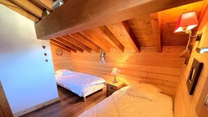 A cozy wooden cabin room with two beds, a nightstand, and a hanging heart decoration. - Chalet, 160m from resort center, view mountain, terrace, parking, tv, ski locker, 65m² (Saint-Martin-de-Belleville)
