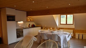 Eine moderne Küche mit weißen Schränken, einem eingebauten Backofen und einem Essbereich mit Tisch für vier Personen.