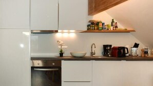 Eine moderne Küche mit weißen Schränken, einem Backofen, einer Spüle und einer Kaffeemaschine.