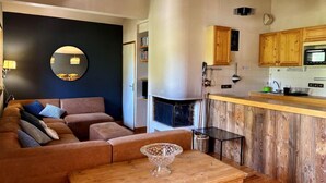 A cozy living room with a sofa, a coffee table, and a kitchen area with wooden cabinets and a microwave. - 100m from ski slopes, 3rd floor, balcony, fireplace or stove, tv, 75m², Pralognan-la-Vanoise (Pralognan-la-Vanoise)