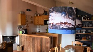 A cozy kitchen with wooden cabinets, a wooden island, and a hanging light with a snowy village scene. - 100m from ski slopes, 3rd floor, balcony, fireplace or stove, tv, 75m², Pralognan-la-Vanoise (Pralognan-la-Vanoise)