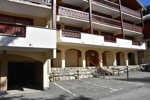 Ein mehrstöckiges Gebäude mit Balkonen, einem Parkplatz und einer Steinmauer.
