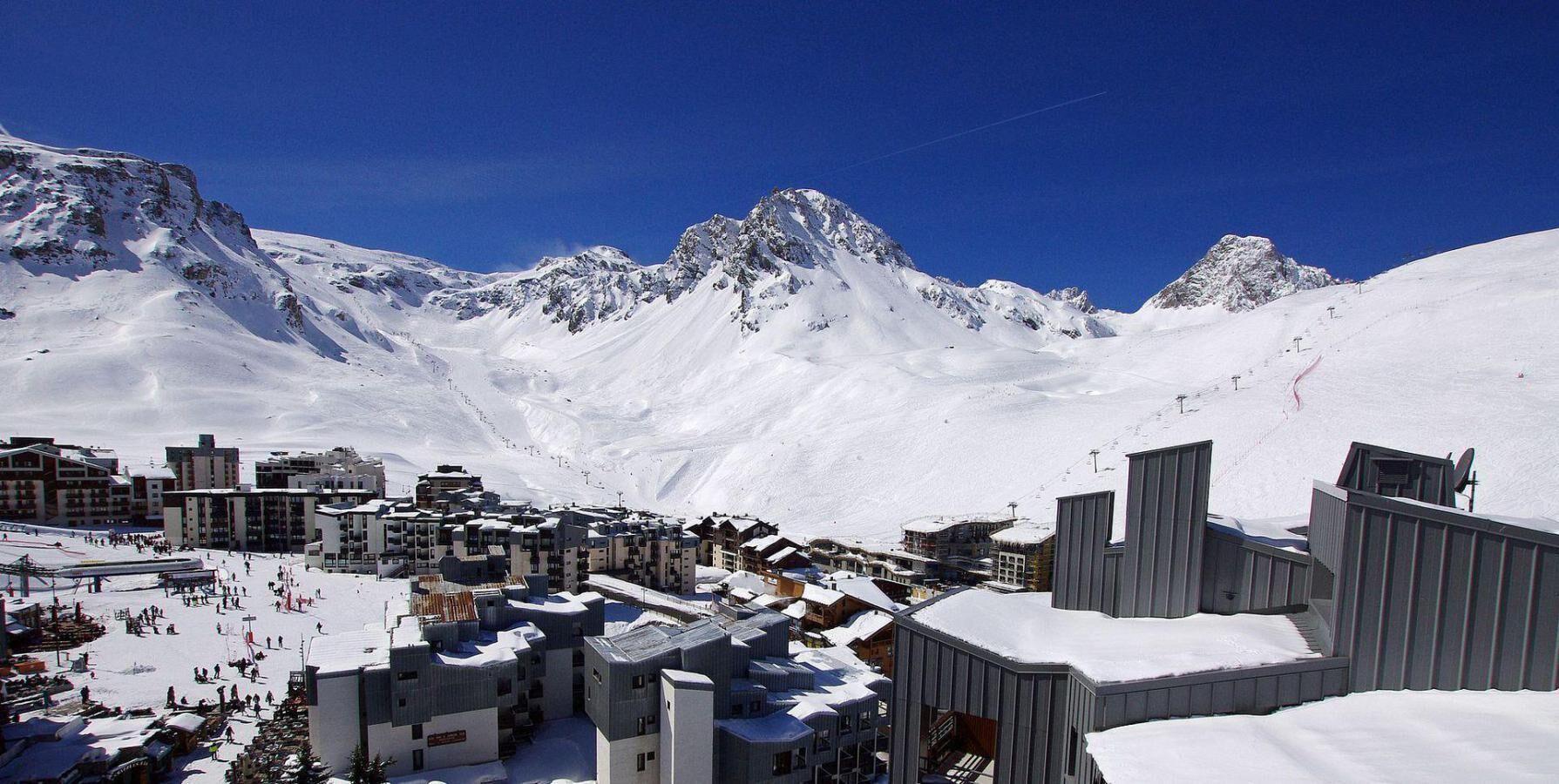A snow-covered mountain town with buildings and ski slopes.