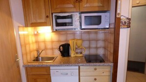A compact kitchen with wooden cabinets, a Bosch dishwasher, a sink, and a microwave.