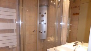 A modern bathroom with a glass-enclosed shower, a white sink, and a toilet.