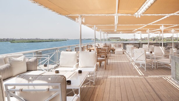 A deck with outdoor seating, a railing, and a view of the water.