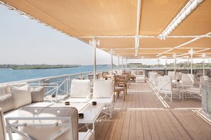 A deck with outdoor seating, a railing, and a view of the water. - Jaz Elite Regent Nile Cruise - Every Monday from Luxor for 07 & 04 Nights - Every Friday From Aswan for 03 Nights (Luxor)