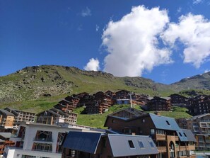Une station de montagne avec des bâtiments de style chalet, des remontées mécaniques et un ciel d’un bleu éclatant.
