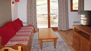 A cozy room with a wooden sofa, a small wooden table, and a TV on a wooden cabinet.