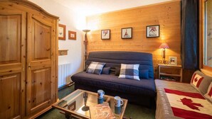 A cozy room with a dark blue sofa, a wooden wardrobe, a glass coffee table with a mug, and a Canadian flag on the bed.