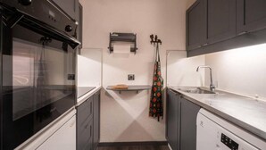 A compact kitchen with a stove, oven, and dishwasher. There is a small countertop and a sink.